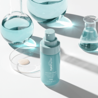 Three pieces of Hydropeptide Anti-Wrinkle + Sensitive Skincare in teal bottles coming out of a splash of water